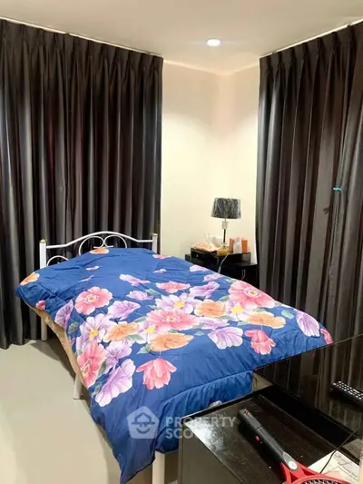 Cozy bedroom with floral bedding and dark curtains, perfect for relaxation.