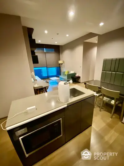 Modern open-layout kitchen with sleek appliances and cozy living area in a stylish apartment.