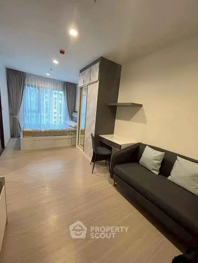 Modern studio apartment with cozy living area and large window view.