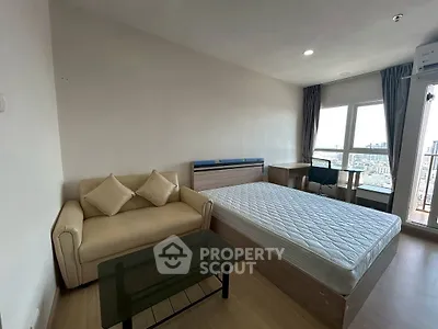 Modern bedroom with city view, featuring a cozy sofa and sleek glass table.