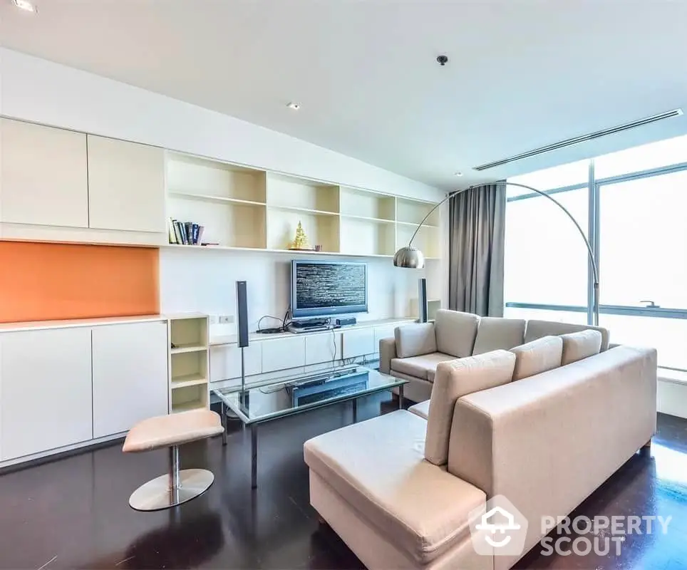 Modern living room with sleek furniture and large window offering natural light.