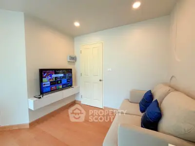 Modern living room with cozy sofa and wall-mounted TV in a bright apartment.