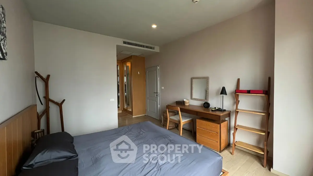 Modern bedroom with sleek furniture and neutral tones, featuring a cozy bed and stylish desk area.