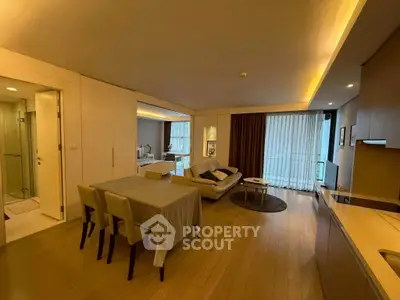 Spacious modern living room with dining area and open kitchen, featuring elegant lighting.