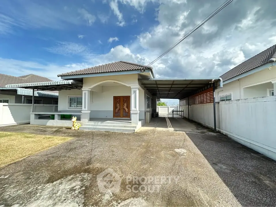 Charming single-story house with spacious driveway and covered carport under a clear blue sky.