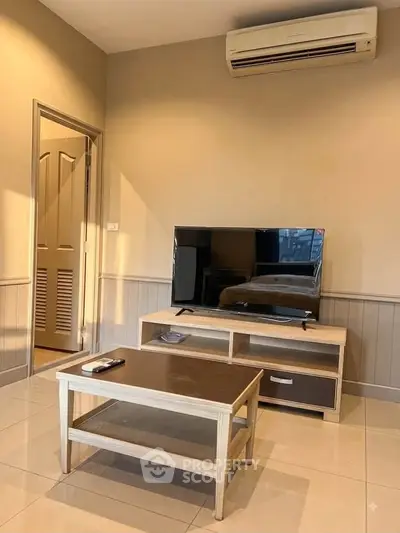 Cozy living room with modern TV setup and air conditioning, perfect for relaxation.