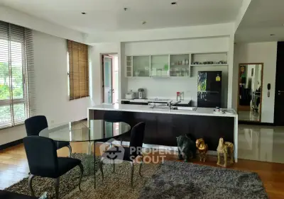 Modern open-layout kitchen and dining area with stylish decor and large windows.