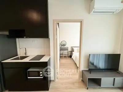 Modern compact apartment with sleek kitchen and cozy bedroom view.