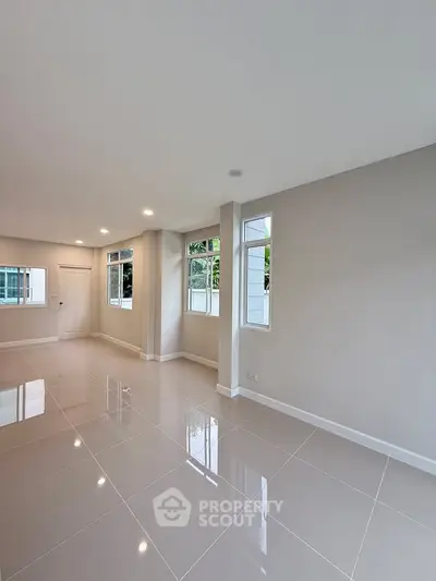 Spacious modern living room with glossy tiled floors and large windows for natural light.