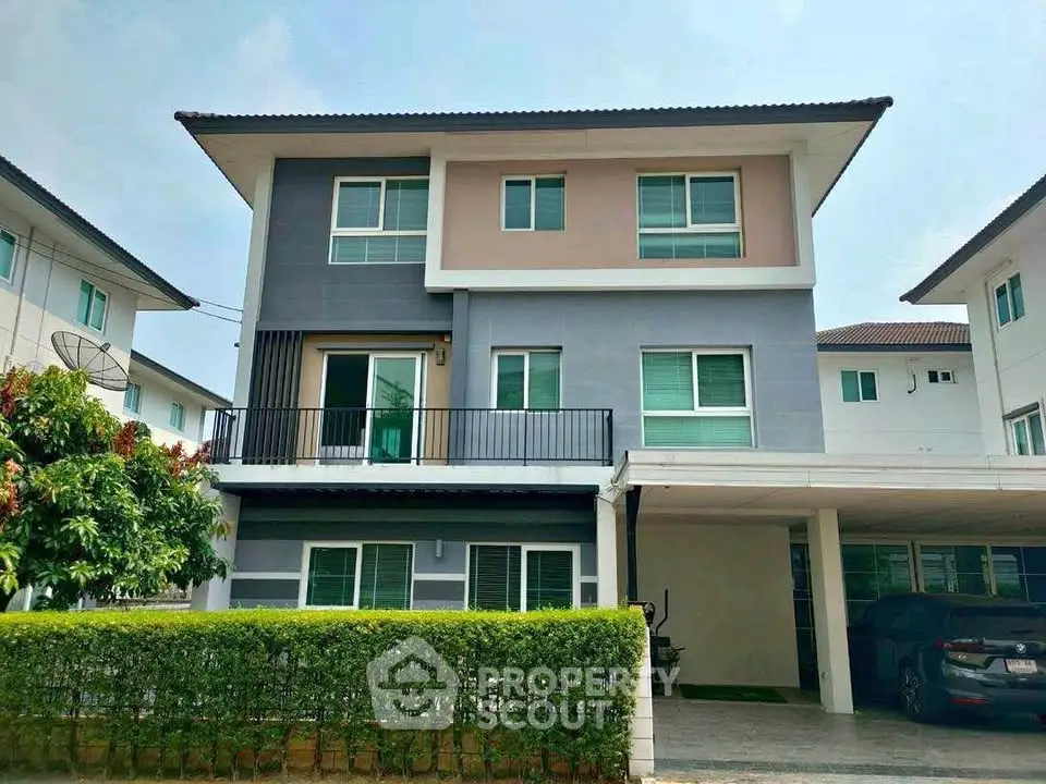 Modern three-story house with sleek design and spacious driveway in a suburban neighborhood.