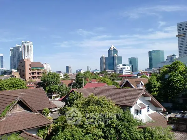 Stunning cityscape view with modern skyscrapers and charming residential rooftops under a clear blue sky.