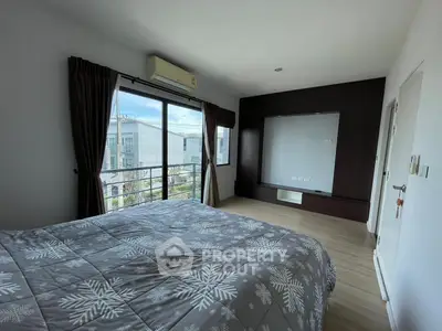 Spacious bedroom with large window and modern decor in a stylish apartment.