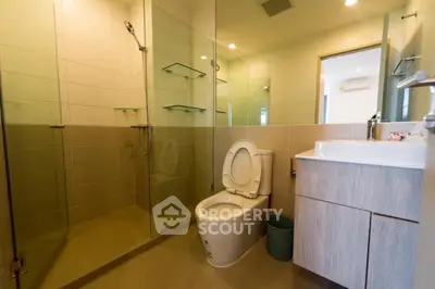 Modern bathroom with glass shower and sleek vanity in contemporary home.