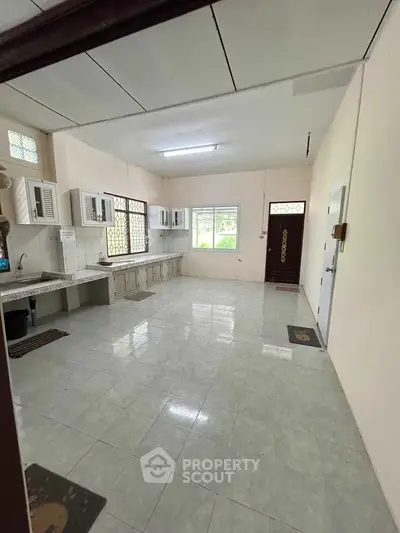 Spacious kitchen with tiled flooring and ample natural light, featuring a closed layout and modern cabinetry.