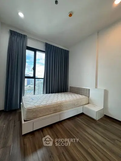 Spacious bedroom with large window offering city views, featuring modern flooring and minimalist design.