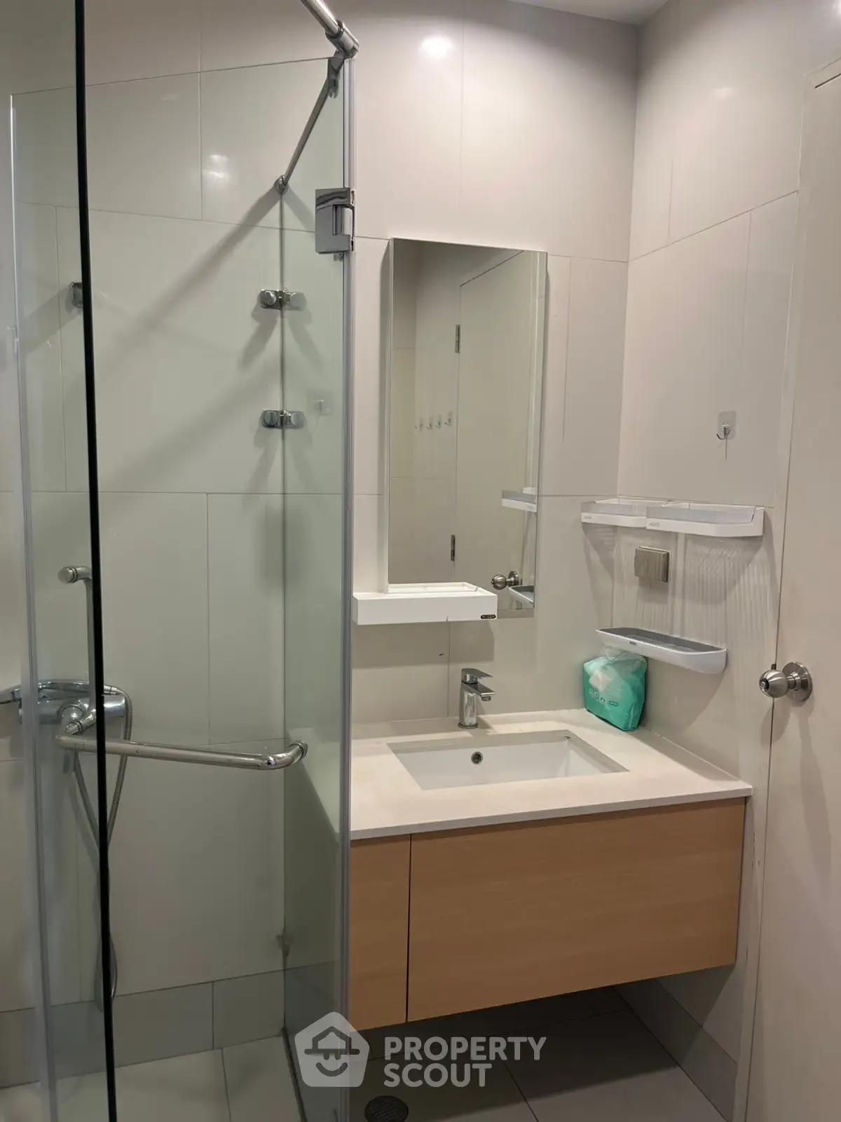 Modern bathroom with glass shower and sleek vanity in contemporary apartment.