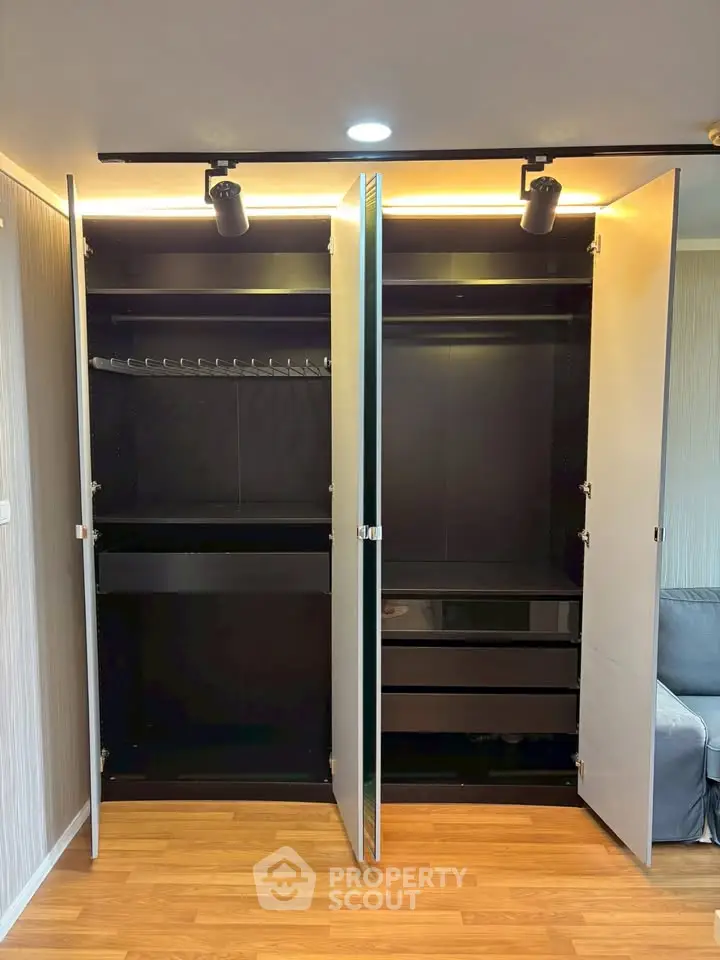 Spacious modern wardrobe with sleek black interior and ample storage space in a stylish apartment.
