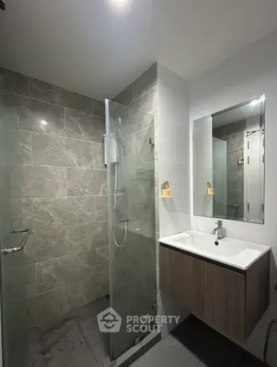 Modern bathroom with glass shower and sleek vanity in contemporary apartment.