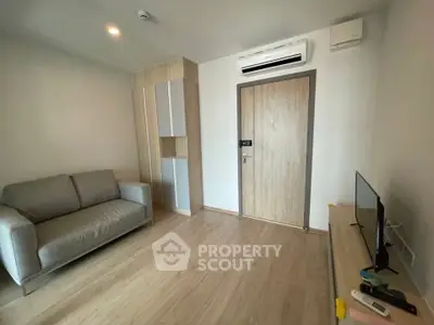 Modern living room with sleek design, featuring a comfortable sofa and wall-mounted air conditioning unit.