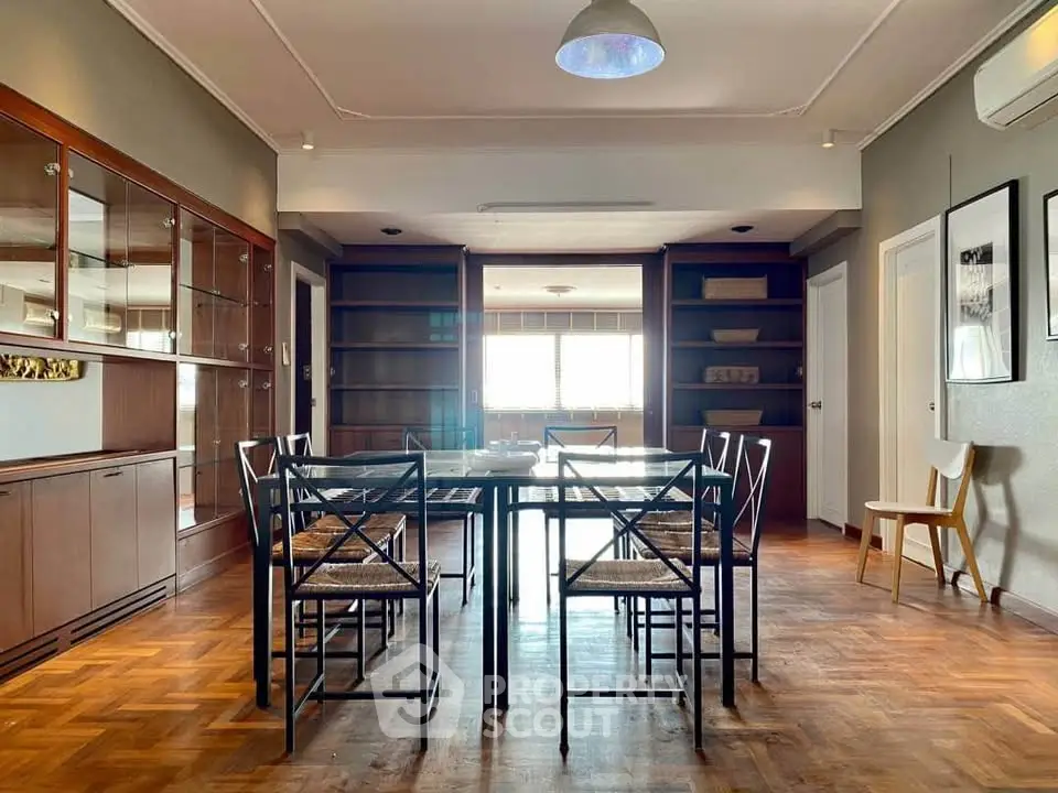 Spacious dining area with elegant wooden flooring and modern furniture in a stylish apartment.