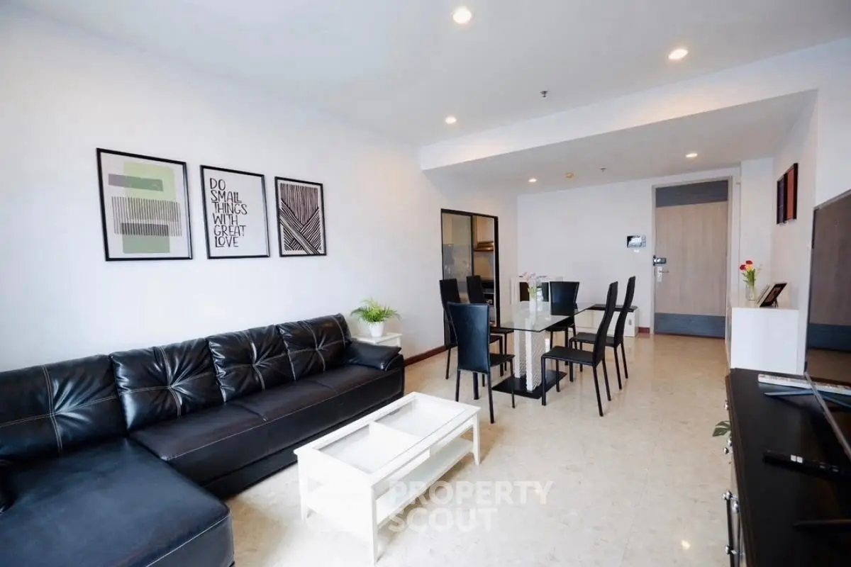 Spacious modern living room with sleek black sofa and elegant dining area