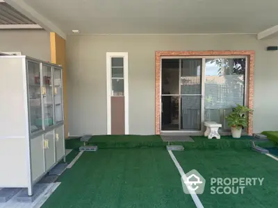 Charming home entrance with artificial grass and sliding glass door