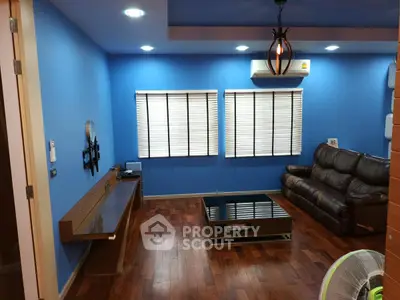 Modern living room with blue walls, wooden flooring, and stylish furniture