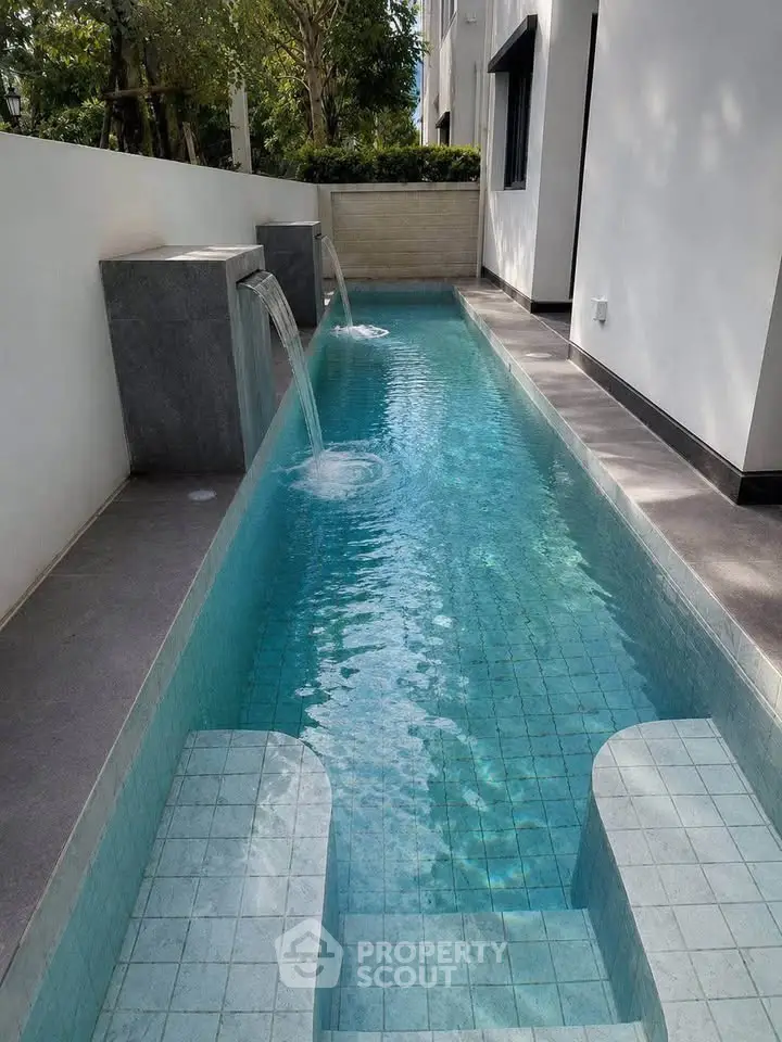 Luxurious narrow swimming pool with elegant water features in modern outdoor setting.
