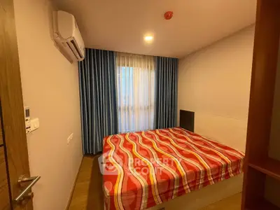 Cozy bedroom with modern decor and vibrant bedspread, featuring air conditioning and natural light.