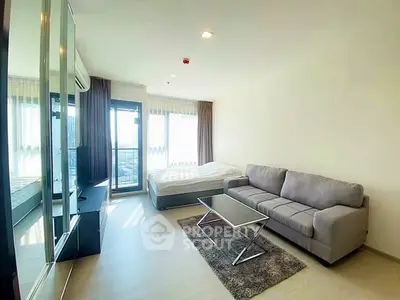 Modern studio apartment with cozy living area and large windows offering natural light.