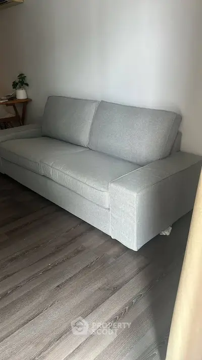 Modern living room with sleek gray sofa and stylish wooden flooring.