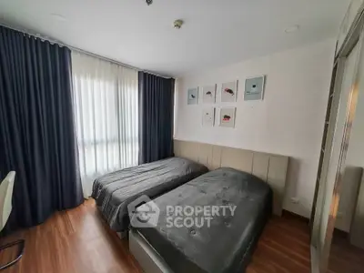 Modern bedroom with twin beds and stylish decor in a well-lit apartment.
