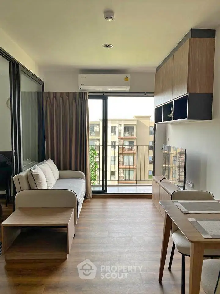 Modern living room with balcony view, featuring sleek furniture and abundant natural light.