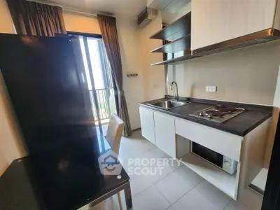 Modern kitchen with sleek cabinetry and balcony view in a stylish apartment.