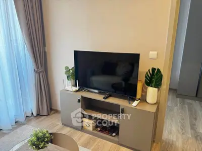 Modern living room with stylish TV stand and decor, featuring natural light and elegant curtains.