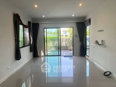 Spacious living room with large windows and pool view, perfect for natural light and relaxation.