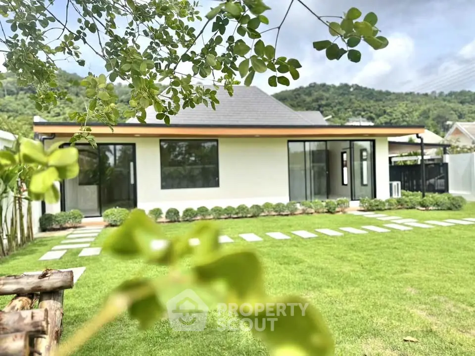 Charming modern house with lush green garden and scenic mountain backdrop