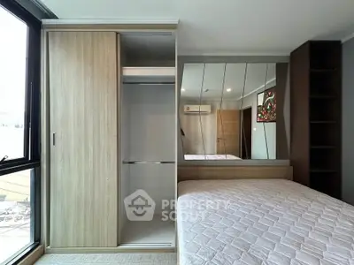 Modern bedroom with built-in wardrobe and large mirror reflecting natural light.