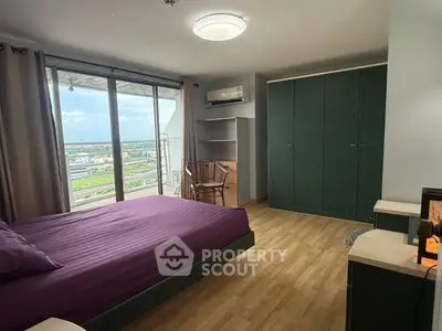 Spacious bedroom with large windows offering stunning city views and ample storage space.