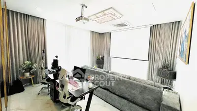 Spacious living room with modern decor, featuring a large sofa, dual workstations, and a ceiling projector.