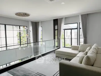 Luxurious modern living room with elegant chandelier and large windows offering natural light.