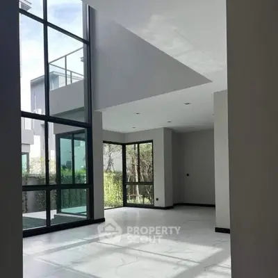 Spacious modern living room with high ceilings and large windows offering natural light.
