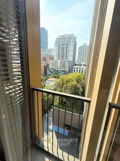 Stunning urban view from a high-rise balcony overlooking cityscape and greenery.