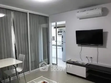 Modern living room with sleek furniture and air conditioning, adjacent to a contemporary kitchen.