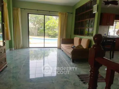 Spacious living room with pool view and elegant tile flooring, perfect for relaxation and entertaining.