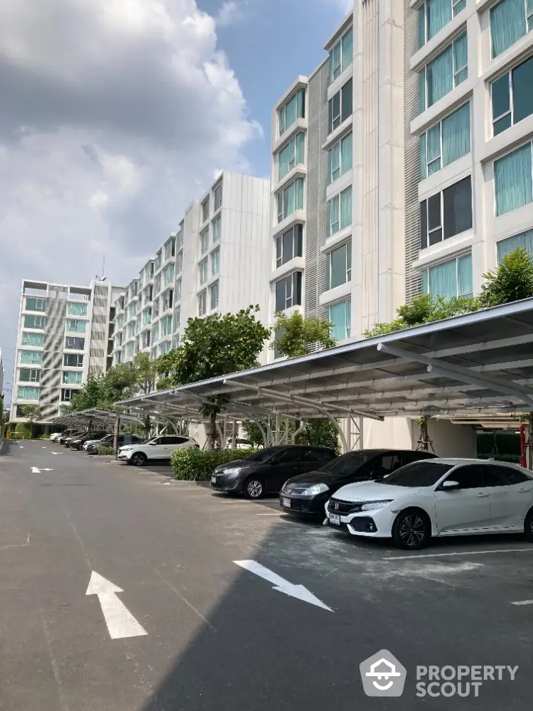 Modern apartment building with spacious parking area and lush greenery