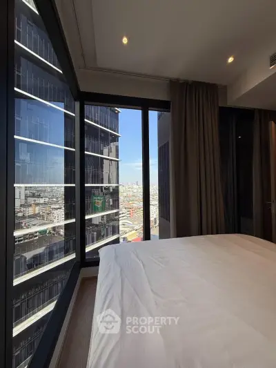 Luxurious bedroom with panoramic city view from floor-to-ceiling windows in a modern high-rise apartment.