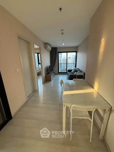 Modern apartment interior with open living and dining area, featuring large windows and city view.