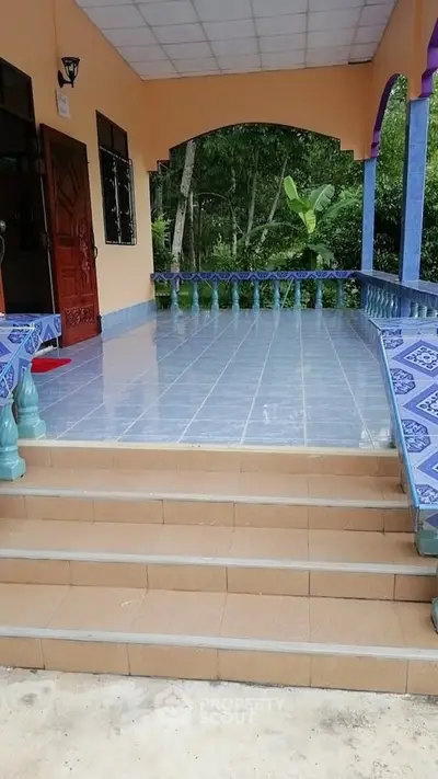 Charming tiled entrance with vibrant blue accents and lush greenery.