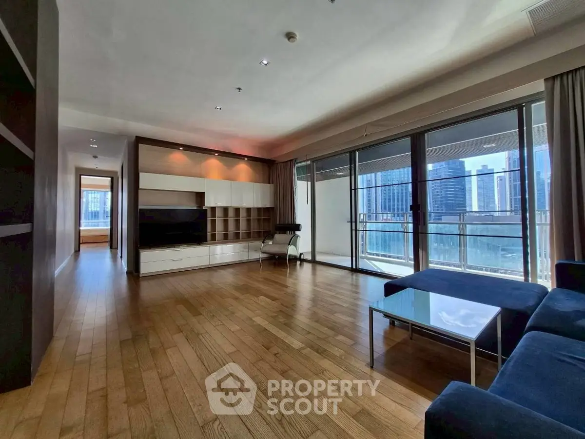 Spacious living room with hardwood floors and city view balcony in modern apartment.